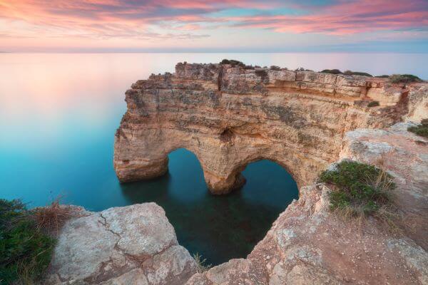 Natürlicher Felsenbogen über dem Ozean an der Marinha-Bucht in der Algarve, Lagoa, Portugal, mit beeindruckenden Höhlen und klarem Wasser im Sommer