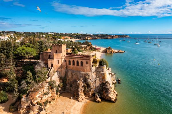 Das Fort São João do Arade (Schloss von Arade) im Dorf Ferragudo an der Algarve, mit dem angrenzenden Strand und der Festung im Hintergrund.