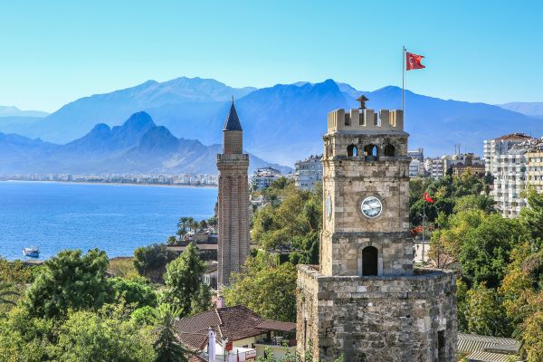 Blick auf die Burg in Antalya mit einer Uhr auf dem Turm und der türkischen Flagge im Wind