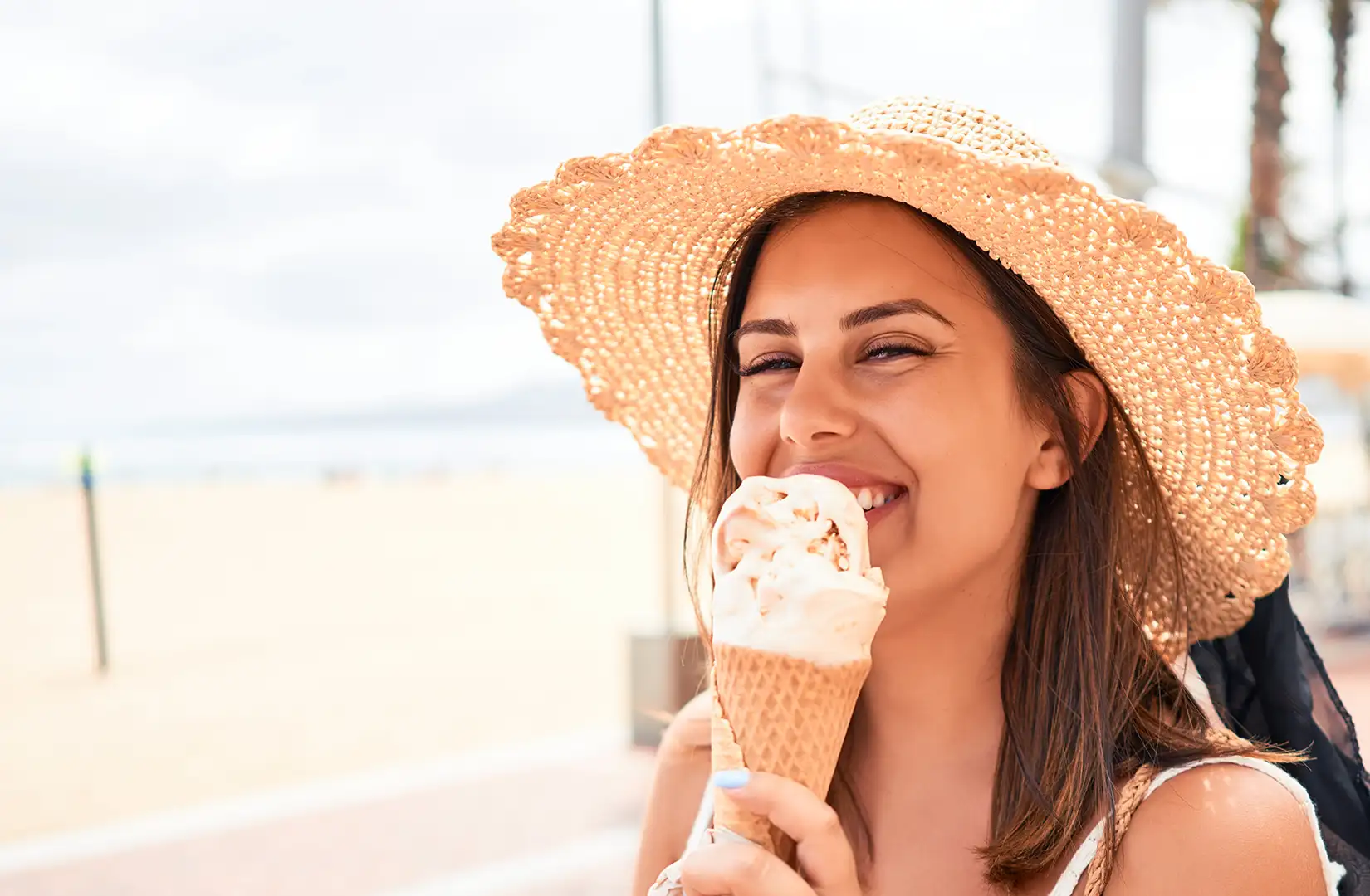 Frau beim Eis-Essen Eine junge Frau läuft entlang einer Strandpromenade und genießt ein Eis