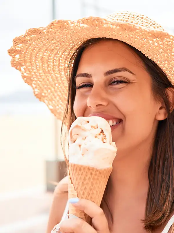 Junge Frau beim Eis-Essen Eine junge Frau läuft entlang einer Strandpromenade und genießt ein Eis